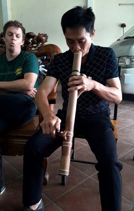 man smoking through long bamboo pipe